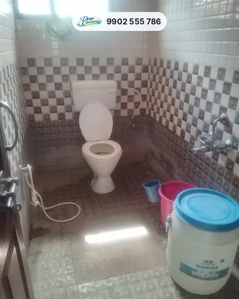 Bathroom with checkered wall tiles and a stained, wet floor