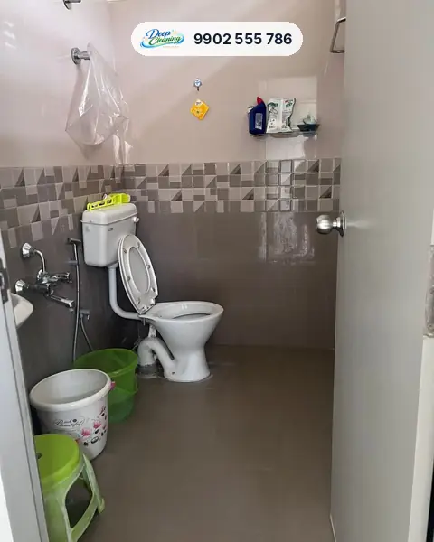 Small tiled bathroom with western commode, taps and buckets