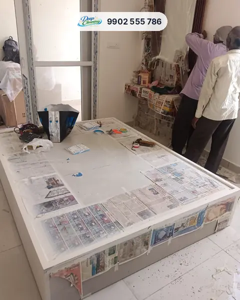 Carpenters fitting panels in a bedroom with furniture covered in newspaper