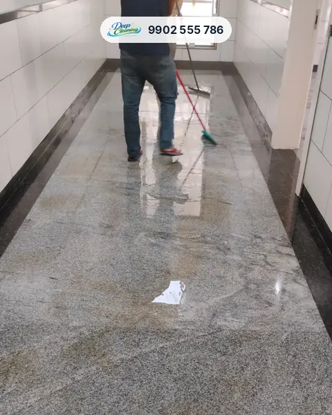 Crew member scrubbing a wet granite corridor floor