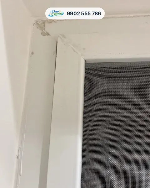 Window frame corner with dried putty and paint splashes above the mesh