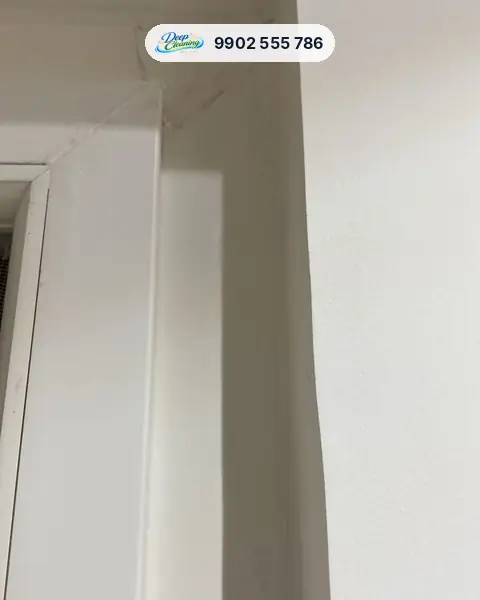 Door frame corner with masking tape and paint residue near the ceiling