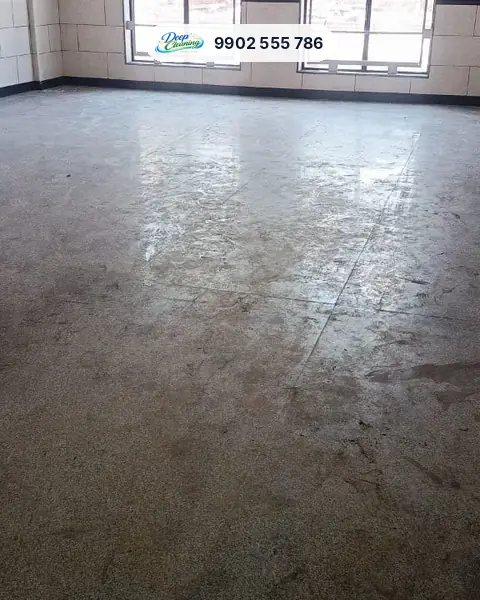 Large hall with tiled walls and a dusty, stained granite floor