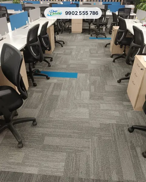 Open-plan office floor with grey carpet tiles, desks and chairs