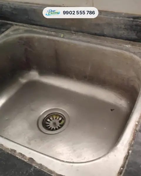 Steel kitchen sink with grease and dark grime along the edges