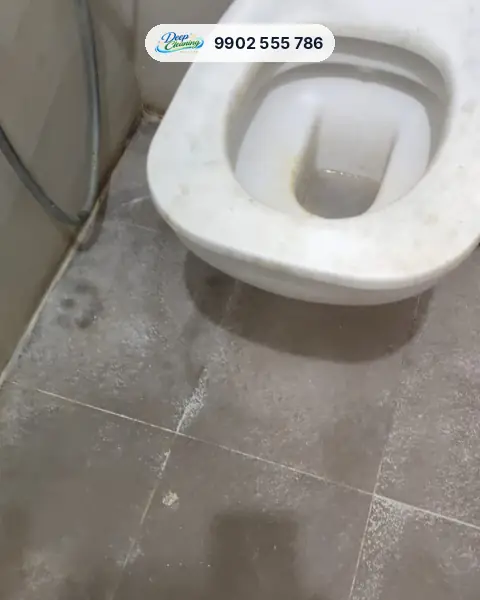 Wall-hung commode with stains and white dust on the dark floor tiles
