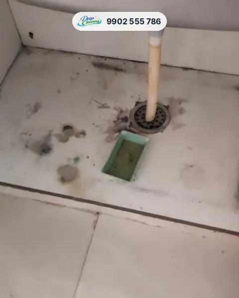 Under-sink cabinet base with water marks and stains around the drain