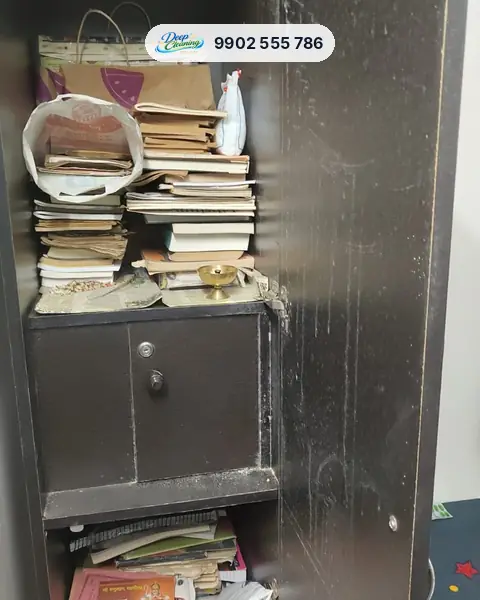 Open wardrobe with stacked books and dust on the shelves and door